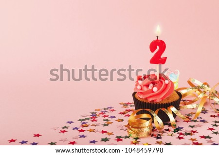Second birthday cupcake with candle and sprinkles on pink background. Card mockup, copy space. Birthday, party, holiday concept