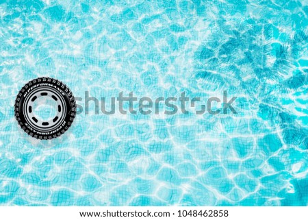 Pool float, ring floating in a refreshing blue swimming pool with palm tree leaf shadows in water

