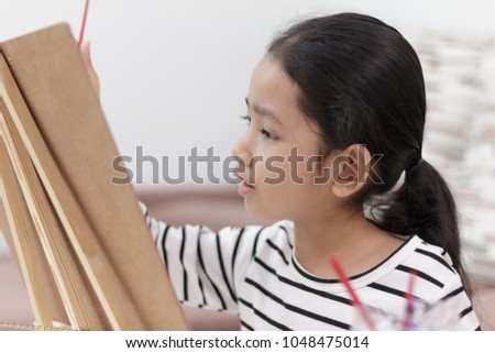 hand girl holding a red paintbrush draws picture at home