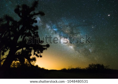 A night time desert landscape scene with the milky way in the backdrop.