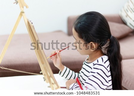 hand girl holding a red paintbrush draws picture at home