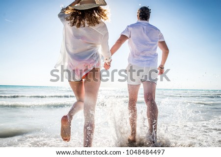 Couple strolling at the beach and smiling - Young adults enjoying summer holidays on a tropical island