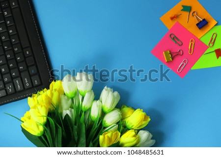 office workspace. artificial flowers, stationery, keyboard. toned background