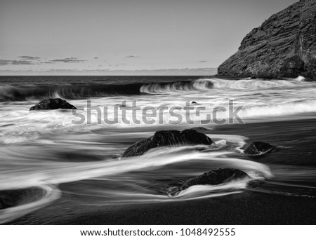 Strong surf on a black volcanic beach with stones, water movement in long exposure - Picture in black and white - Location: Spain, Canary Islands, La Palma