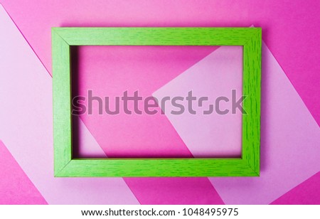Green photo frame on pink background top view