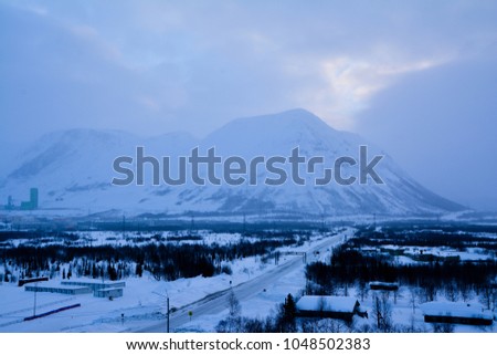 Beautiful winter scene with icy slick road driving situation curving road covered with snow and snowy trees all around on snow mountain background.
