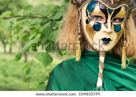 Beautiful woman in carnival mask over foliage background