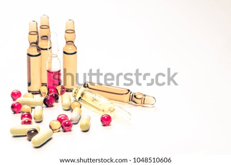 Colorful vitamin ampoules, and medicine capsules on an abstract white background. Healthcare, medical and pharmaceutical concept. Detailed close up studio shot with soft selective focus. Toned