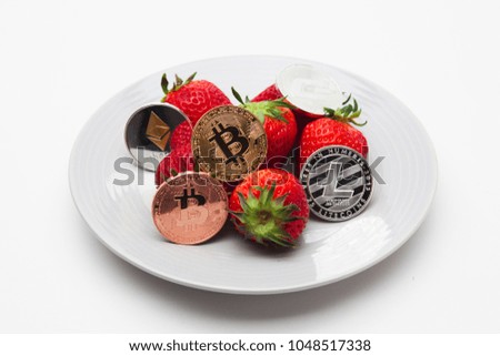 Strawberries and cryptocurrency arranged on plate isolated 