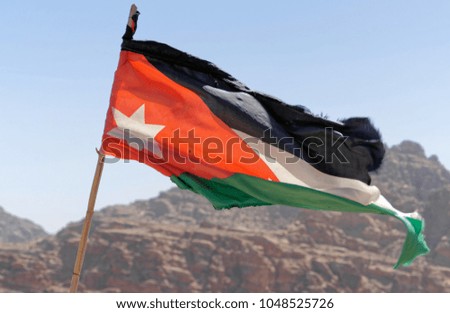 Slightly battered flag of the land Jordan on the high windy cliffs of Petra, Wadi Musa, Jordan, middle east
