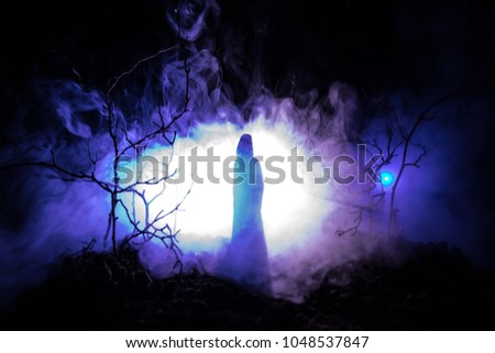 Alone girl with the light in the forest at night, or blue toned night forest at the fog time