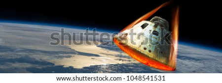 A space capsule reenters the earths atmosphere causing the heat shield to glow from the friction of tremendous speed. Elements of this image courtesy of NASA. Royalty-Free Stock Photo #1048541531