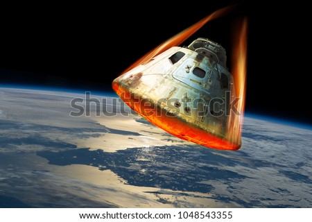 A space capsule reenters the earths atmosphere causing the heat shield to glow from the friction of tremendous speed. Elements of this image courtesy of NASA. Royalty-Free Stock Photo #1048543355
