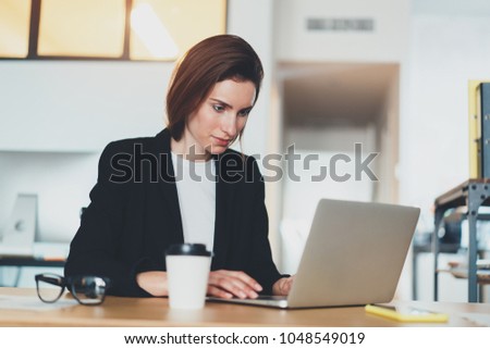 Handsome businesswoman using laptop computer at modern office.Blurred background.Horizontal