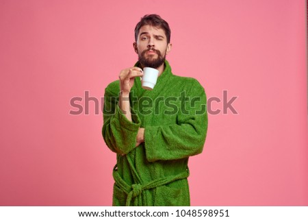  man in green dressing gown with mug, drink                               Royalty-Free Stock Photo #1048598951