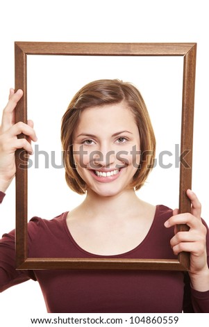Happy attractive woman in empty wooden picture frame
