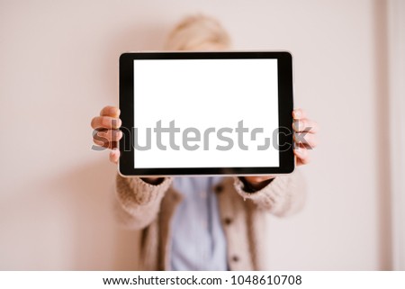 Close up focus view of tablet in a horizontal position with a white editable screen while a blurred woman holding it.