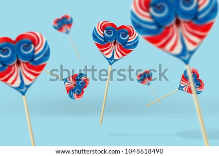 Colorful lollipop on blue pastel background. Candy bar in shape of a hearth flying around . Christmas holiday design concept elements. Candy Shop concept.