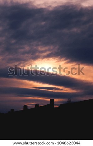 Dramatic evening sunset sky with clouds over rooftops
