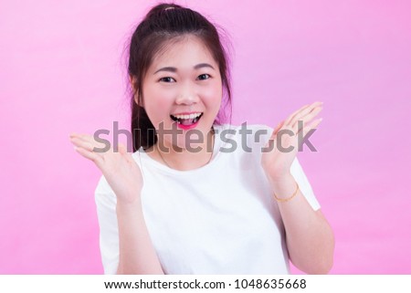 Portrait of beautiful Young Asian woman black hair wear a white t-shirt with open hand. Happy and bright feeling. Cute lovely girl looking at camera with adorable smile. isolated on pink background.
