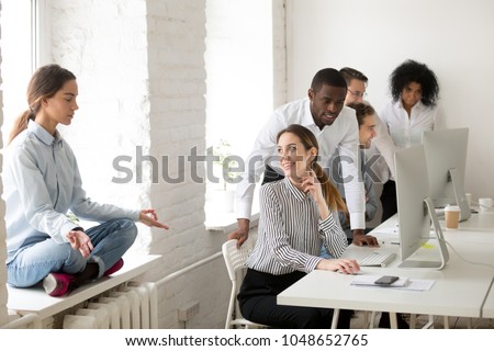 Young woman meditating practicing yoga sitting at office sill avoiding colleagues looking at girl with ironical smile, mocking and making fun of weird coworker, jeering or bullying at work concept Royalty-Free Stock Photo #1048652765