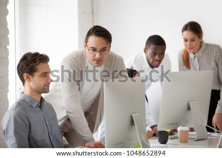 Corporate mentor teaching intern helping and supervising online computer work, team leader or company executive explaining new web design project or programming task to employee at workplace Royalty-Free Stock Photo #1048652894