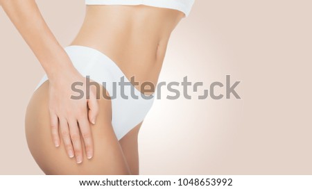 woman dressed in white underwear , standing on beige pastel color background. Perfect body and stomach, close-up.