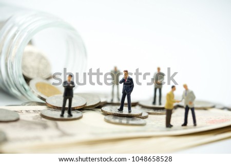 Miniature people: business man making decision on banknotes and coins stacks, success, dealing, greeting and partner concept.