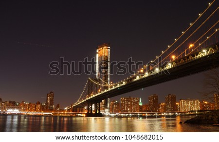 Manhattan Bridge at night as seen from Brooklyn Bridge Park in New York City.