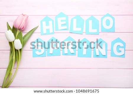 Inscription Hello Spring with tulip flowers on pink wooden table