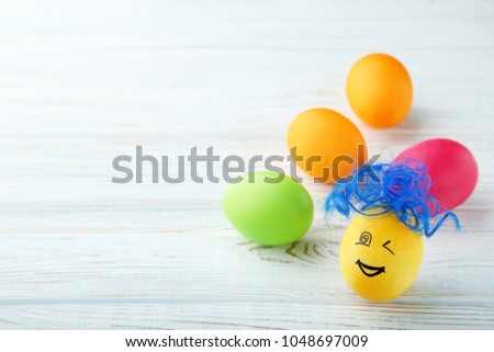 Egg with funny face and blue hair on wooden table