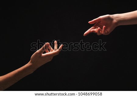 Male and female hands reaching each other on black isolated studio background. Love, relations, support, together forever concept. Copy space, cutout, low key