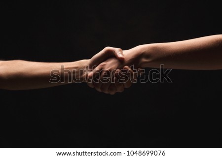Male and female hands holding tight together on black isolated background. Love, relations, support, together forever concept. Copy space, cutout, low key