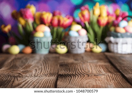 
Easter background. Rustic wooden table. Tulips and spring flowers. Easter eggs. Colorful bokeh. Place for typography. 