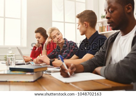 Diverse students studying together. Young casual multiethnic people preparing for exams, reading books and surfing the web on laptop. Co-working and education concept, copy space