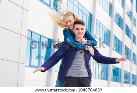 Beautiful young couple, brunette boy and blonde hair girl, enjoy city street, has fun smile. They clothed blue jeans jacket.  Urban portrait. Happy people. Close up. Spring fashion style. 