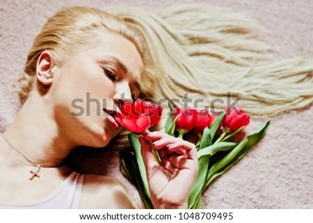 beautiful blonde is sniffing a bouquet of tulips