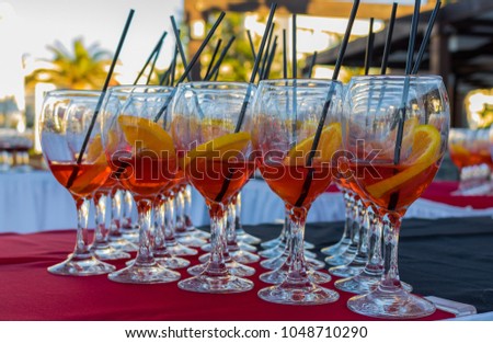 Aperol Spritz cocktails served as an aperitif of a professional catering in high class holiday club. Drinks before dinner. Glasses filled with alcohol, orange slices, ice and straws.