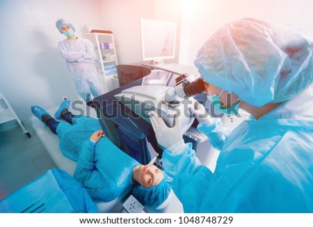 Laser vision correction. A patient and team of surgeons in the operating room during ophthalmic surgery. Eyelid speculum. Lasik treatment. Patient under sterile cover Royalty-Free Stock Photo #1048748729