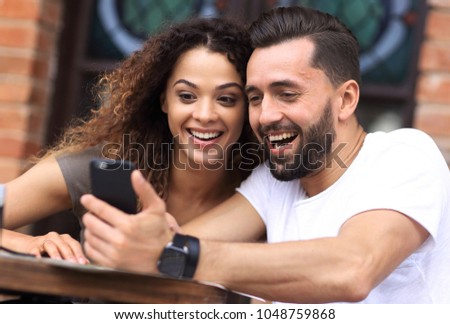 Portrait of a young  couple sitting down at a cafe terrace