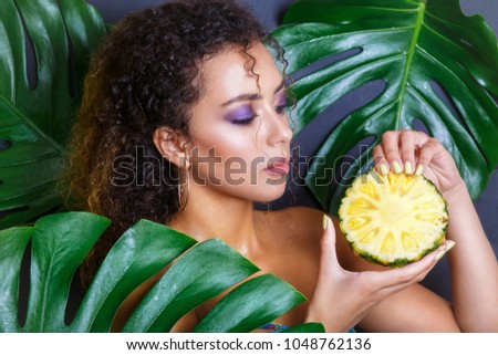 Close-up of beautiful afro girl with pineapple posing in tropical forest