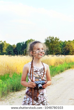 Cute little girl taking pictures with old film camera.  Pretty child in nature. Place for text