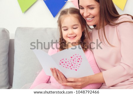 Mother and daughter together at home celebration concept sitting reading greeting card