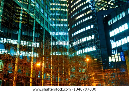 Illuminated office buildings in Paris business district La Defense. Night city lights, skyscrapers glass facades. Modern urban architecture, economy, finances, business activity concept.
