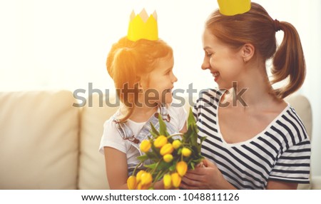 happy mother's day! mother and child daughter in crowns and with flowers yellow tulips

