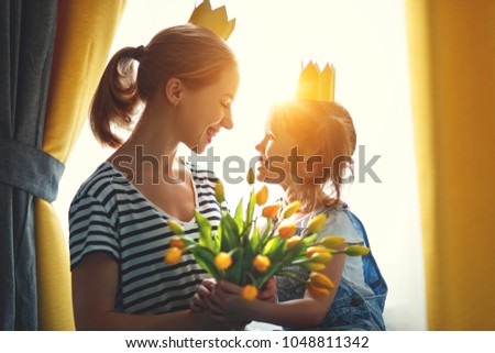 happy mother's day! mother and child daughter in crowns and with flowers yellow tulips
