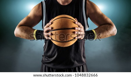 Basketball ball in a male hands, player in black with orange sport ball.