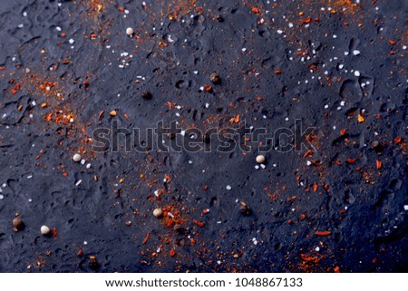 Red spices, salt and pepper on black marble. Black abstract background. Top view.