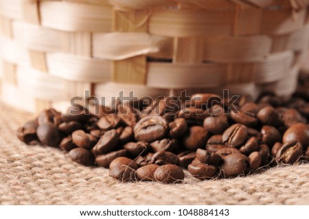 Close-up of brown coffee beans and wicker basket on a beige