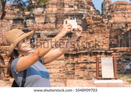 woman traveler with backpack and hat and take a photo with smartphone with historical park  background from Ayutthaya near Bangkok Thailand. Traveling Thailand.
